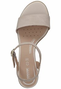 Sandalo in suede beige con una larga fascia sul piede, cinturino regolabile alla caviglia con hardware dorato e soletta imbottita con design perforato.