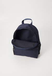 Sac à dos bleu marine en tissu durable, avec un compartiment principal zippé et une poche avant zippée. Comprend une poignée supérieure.
