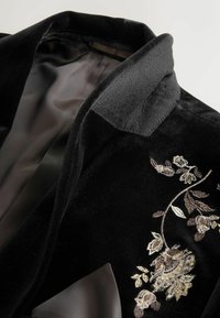 Black velvet blazer featuring a sleek design with a notched collar and intricate floral embroidery in gold and silver threads.