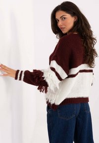 Sweter dziany w kolorze burgundowym i białym, z teksturowanymi frędzlami na rękawach, opuszczonymi ramionami i luźnym krojem.