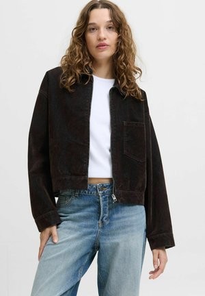 Donkerbruine cropped jack met een ritssluiting aan de voorkant, een enkele borstzak en brede mouwen, gecombineerd met blauwe high-waisted jeans.