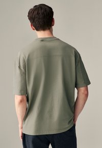 Kortærmet T-shirt i salviegrøn lavet af blødt bomuldsblandet stof; har en lige pasform, rund halsudskæring og diskrete sømdetaljer på ryggen.