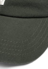 Groene katoenen baseballcap met een gestructureerde kroon, gebogen rand, zichtbare stiksels en een textuurstofoppervlak. Geen logo's of versieringen.
