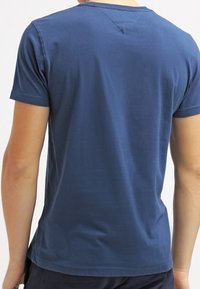 Krátký rukáv, tmavě modré tričko vyrobené z bavlny, s klasickým kulatým výstřihem, hladkou texturou a decentním V-štípáním vzadu.