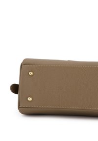 Beeigefarbenes Lederhandtaschen-Basis mit strukturiertem Finish, akzentuiert durch goldene Nieten und kontrastierende Nähte. Eine kleine Schlaufe zur Befestigung ist sichtbar.