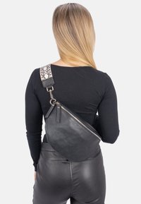 Schwarze Leder-Crossbody-Tasche mit strukturierter Oberfläche, ausgestattet mit einem gemusterten, verstellbaren Tragegurt und einem Reißverschluss.
