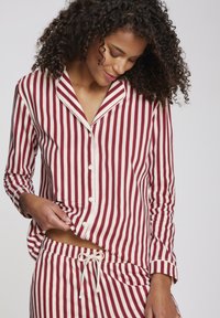Gestreepte katoenen pyjamastel met rode en witte verticale strepen, een notch-kraag en een overhemd met knopen, vergezeld van bijpassende broek met touwtjes.