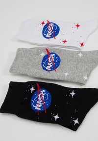 Tris porų kojinių: baltos, pilkos ir juodos. Kiekvienos su NASA logotipu mėlyna spalva, raudona juosta ir mažais baltais žvaigždžių raštais.
