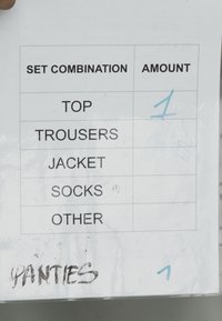 Liste der Bekleidungsstücke: Oberteil, Hose, Jacke, Socken, andere; handschriftliche Notiz für "Unterhosen." Gedruckt auf weißem Papier, schwarzer Text, teilweise Handschrift.