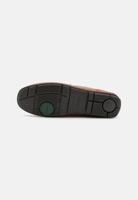Suola in pelle marrone con fondo in gomma nera. Presenta una superficie testurizzata per aderenza, un logo verde circolare e scanalature distinte per la trazione.