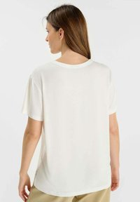 Witte T-shirt met korte mouwen en ronde hals, met een zachte textuur. Het heeft een relaxed fit en een label aan de zoom.