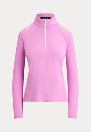 Pull lavande à manches longues avec un col montant et une fermeture éclair blanche à l'avant, avec des détails discrets de coutures et un petit logo sur l'épaule.