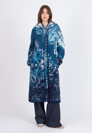 Cappotto lungo lavorato a maglia in sfumature di blu con motivi intricati, un cappuccio e tasche laterali, caratterizzato da una vestibilità snella e rilassata.