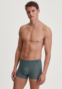 Herenboxershorts in donker teal met een geometrisch patroon. Gemaakt van zachte stof, met een elastische tailleband en een sleutelgat-levensstijl.