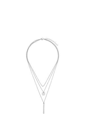 Zilveren gelaagde ketting met drie kettingen van verschillende lengtes, waarvan er één een ronde hanger heeft en de ander een verticale staafaccent.