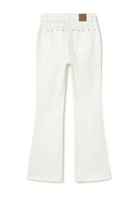 Jeans blancos acampanados con bolsillos traseros que presentan pequeñas tachuelas metálicas en los bordes superiores y una etiqueta de marca de cuero marrón en la cinturilla.