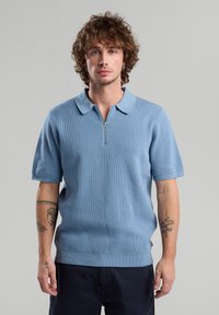 Light blue short-sleeve polo shirt with a ribbed texture and a half-zip opening, featuring a classic collar and a straight hem.