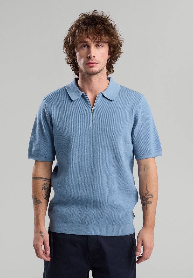 Light blue short-sleeve polo shirt with a ribbed texture and a half-zip opening, featuring a classic collar and a straight hem.