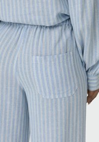 Heldblauwe pyjamabroek met verticale witte strepen, voorzien van een elastische tailleband en een klein zakje op de rechterzijde.