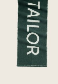 Zielony szalik z napisem "TAILOR" dużymi, białymi literami. Wykonany z miękkiego materiału, z frędzlami na krawędziach i grubą teksturą.