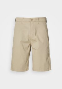 Beige Baumwollshorts mit geradem Schnitt, Knopfverschluss, Gürtelschlaufen und zwei Seitentaschen. Glatte Textur und knielanges Design.