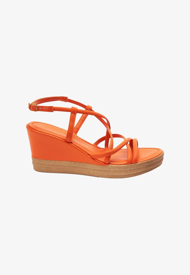 Sandale compensée orange avec des brides croisées et une boucle à la cheville sur une semelle texturée marron clair, vue de profil.