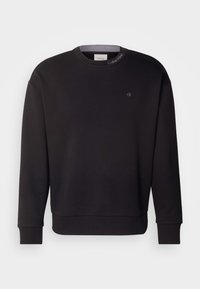 Sweat-shirt noir à manches longues avec col rond, poignets et ourlet côtelés, petit logo "ck" sur la poitrine et texte "Calvin Klein" sur le col.