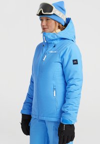 Lichtblauwe geïsoleerde skijack met capuchon, voorzien van ritszakken, verstelbare manchetten en een logo op de borst en mouw.