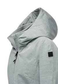 Lys grå jakke med hette, teksturert stoff, frontglidelås og en svart logo-patch på skulderen. Har et elegant, moderne design.