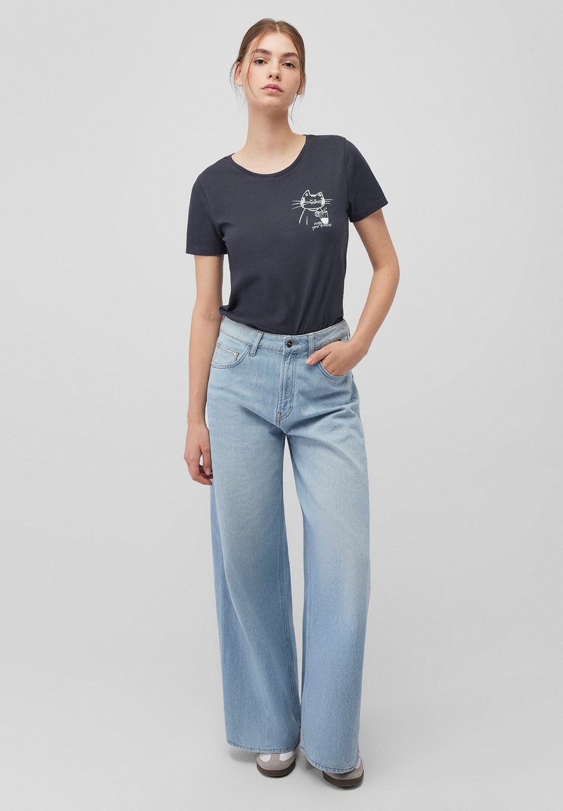 Navy t-shirt with a cat graphic, paired with light blue wide-leg jeans. The jeans have a high waist and a slight fade.