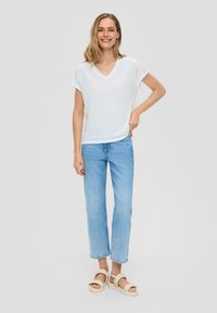 Witte V-hals t-shirt met korte mouwen, lichtblauwe rechte spijkerbroek en beige platform sandalen. Glad materiaal en casual pasvorm.