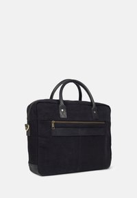 Black canvas laptop bag with leather accents. Features top handles, a front zipper pocket, and a patch of branding. Rectangular shape.