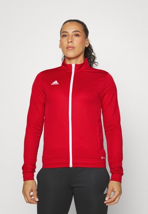 Rote sportliche Zip-Jacke mit hohem Kragen, weißem Reißverschluss und Adidas-Logo auf der linken Brust. Texturierte, taillierte Ärmel.