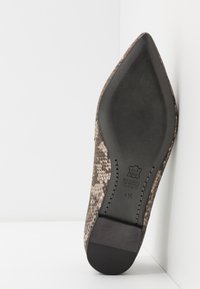 Chaussure à bout pointu en cuir imprimé serpent texturé marron et beige, avec une semelle noire, présentant des coutures visibles et un talon plat.