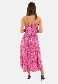 Robe maxi à imprimé léopard rose avec des bretelles fines, un ourlet froncé et une taille cintrée. Tissu lisse avec un design à étages.