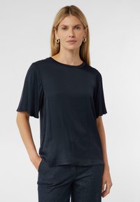 Czarnoniebieski t-shirt z krótkim rękawem wykonany z gładkiego materiału, z okrągłym dekoltem i delikatnie rozszerzanymi rękawami. Prosty, minimalistyczny design.