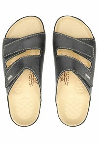 Sandales à glisser en cuir noir avec deux larges sangles, présentant des découpes et des coutures blanches contrastantes. Semelle intérieure en beige rembourrée.