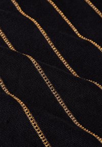 Black fabric with textured appearance, highlighted by alternating gold thread stripes, featuring a delicate lace-like pattern.