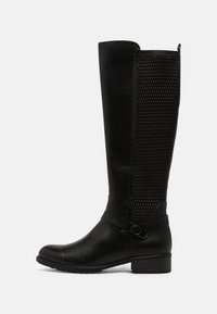 Bota negra hasta la rodilla con parte delantera de cuero liso y un panel de malla texturizada en la parte posterior. Incluye una correa con hebilla y un tacón bajo tipo bloque.