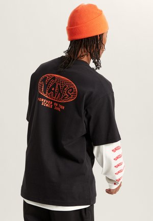 Black cotton T-shirt with red graphic design on the back reading "Vans" and "Forever on Tour." Layered with a white long-sleeve shirt underneath.
