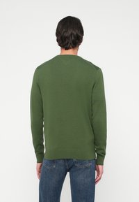 Πράσινο πλεκτό πουλόβερ με μακριά μανίκια, στρογγυλή λαιμόκοψη και ριμπ μανσέτες. Φοριέται με μπλε τζιν παντελόνι. Μαλακή υφή, άνετη εφαρμογή.