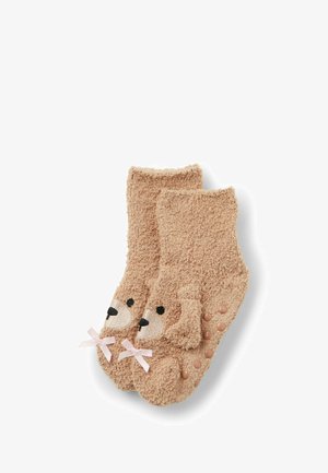 Beige kuschelige Socken mit einem Hundegesicht-Design, schwarzen gestickten Details und rosa Schleifen an den Knöcheln; rutschfeste Silikondots auf den Sohlen.
