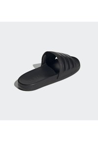 Black slide sandal with a smooth texture, featuring three horizontal stripes on the strap, flat sole, and brand logo embossed on the footbed.
