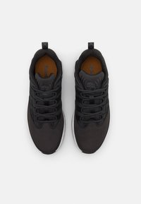 Sapatilhas pretas desportivas com um superior texturizado, biqueira redonda e sola branca contrastante. Apresenta cordões elásticos e um interior forrado suave.