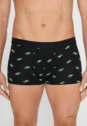 Czarne bokserki w zielony wzór stosów pieniędzy, noszone przez osobę pokazującą dolną część tułowia i górną część ud.