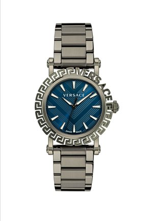 Srebrny metalowy zegarek z niebieską teksturowaną tarczą w wzór jodełki, wyraźnymi znacznikami godzin oraz motywem greckiego klucza na obręczy.