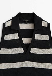 Gilet noir sans manches en tricot avec de larges rayures horizontales blanches et un col côtelé avec un décolleté en V profond.