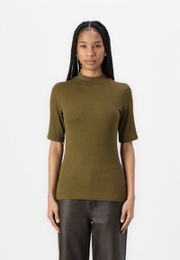 Kaki stripete t-skjorte med høy hals og korte ermer, figursydd design, glatt tekstur, kombinert med mørke skinnbukser.