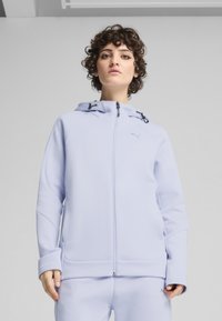 Sweat à zip bleu clair avec capuche, doté de cordons noirs, de poches frontales et d'un logo discret sur la poitrine. Texture douce et lisse.