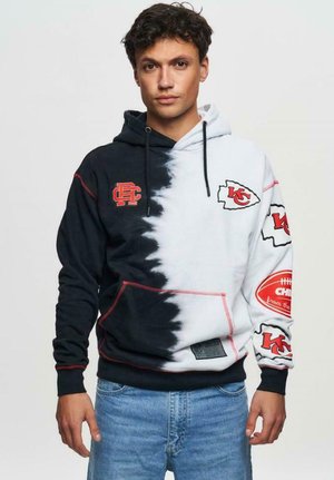 Hoodie featuring a split black and white design with red accents. Displays the Kansas City Chiefs logo and a football graphic on the sleeve.
